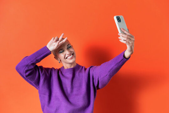 Joyful adult woman in purple sweater taking selfie