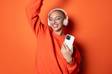 Joyful adult woman dancing with headphones and smartphone