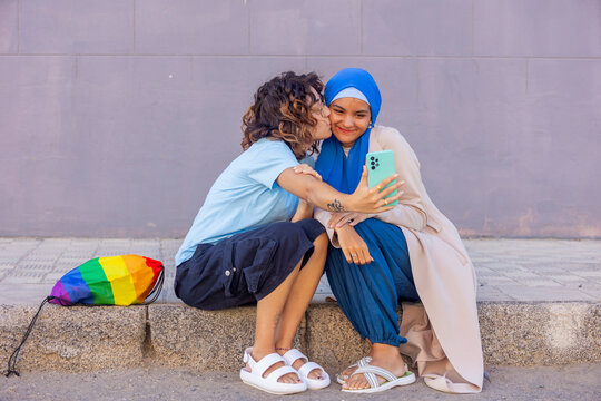 Lesbian couple with muslim partner smiling outdoors