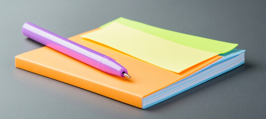 Purple pen resting on orange notebook with sticky notes