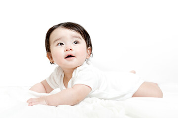 ロンパースを着てハイハイしながら上を見つめる赤ちゃんの横姿