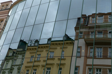 A large, impressive building featuring numerous windows is beautifully reflected in the sleek,...