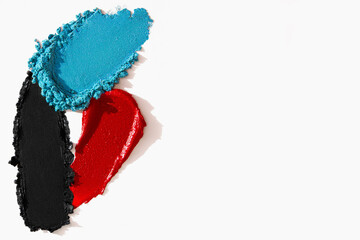 Cosmetic textures of lipstick, eyeshadow, bronzer, glitter, and powder in a colorful composition
