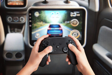 Child gaming on a tablet mounted on the back of the passenger seat, holding a gamepad, showcasing rear-seat entertainment and portable gaming in a car setting