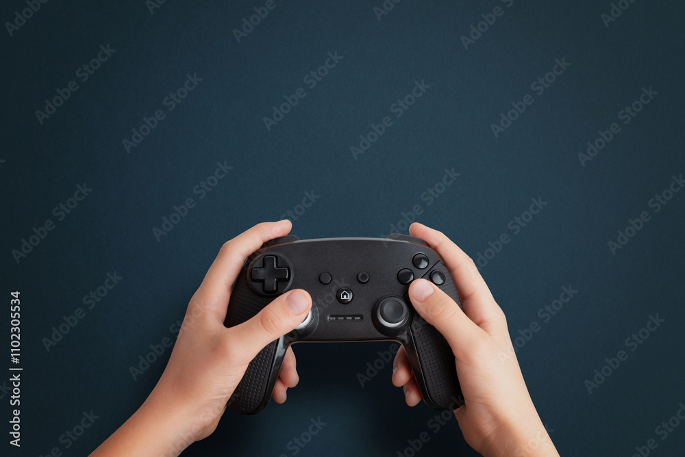 Poster top view of a hand holding a gamepad on a blue desk, flat lay composition with clean space for promo