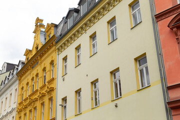 A row of buildings can be seen with a bright yellow building situated right in the center, standing out amidst the others around it