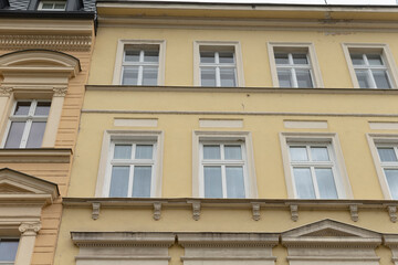Fototapeta premium A tall yellow building adorned with numerous windows that create a vibrant facade and enhance the overall architectural appeal of the structure