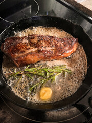 searing steak in skillet with rosemary and butter
