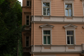 An impressive building that features numerous windows, complemented by trees that are beautifully situated in the background, creating a lovely scene