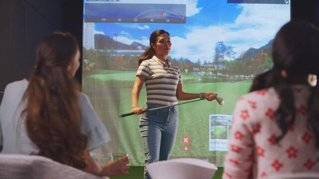 Woman swings a golf putter during a VR game and cheers with her friends