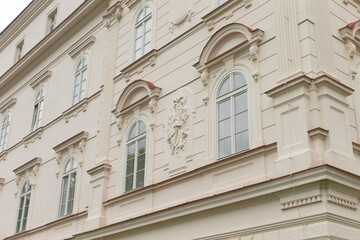There is a large white building that features numerous windows, and prominently displays a clock on its side for keeping time