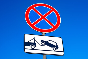 Road signs no stopping, evacuation of cars, against blue sky