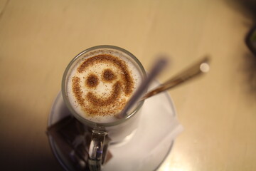 A delightful and cheerful coffee beverage presented in a glass mug with soothing smiley foam art