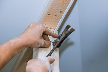 Craftsman carefully using hammer to secure electrical wiring to wooden framing in residential construction project