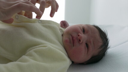 Newborn baby calm and peaceful while nurse dresses and buttons him up in hospital. serene expression on the baby’s face highlights the gentle and tender care 