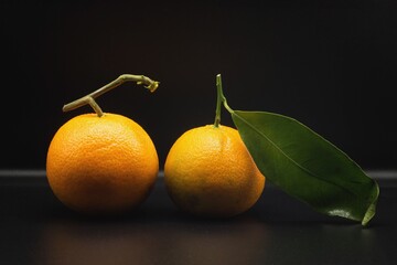 fresh oranges with green leaves on black background