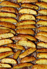 Roasted  potato wedges with olive oil and herbs on a baking sheet.style rustic.selective focus