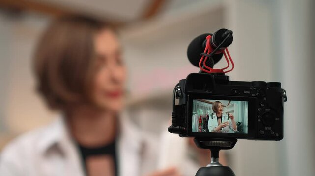 Rear back view behide camera screen display woman influencer shoot live streaming vlog video review skincare for prim social media or blog. Girl with cosmetic studio lighting.