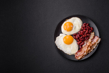 English breakfast with fried eggs, bacon, beans, tomatoes, spices and herbs