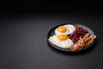 English breakfast with fried eggs, bacon, beans, tomatoes, spices and herbs