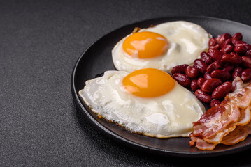 English breakfast with fried eggs, bacon, beans, tomatoes, spices and herbs