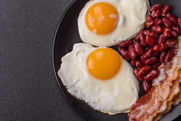 English breakfast with fried eggs, bacon, beans, tomatoes, spices and herbs