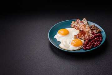 English breakfast with fried eggs, bacon, beans, tomatoes, spices and herbs