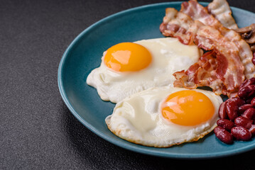 English breakfast with fried eggs, bacon, beans, tomatoes, spices and herbs
