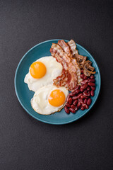 English breakfast with fried eggs, bacon, beans, tomatoes, spices and herbs