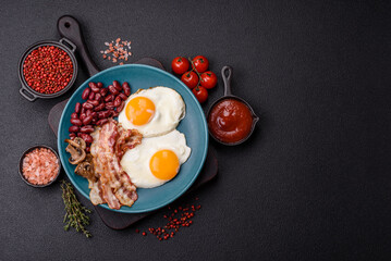 English breakfast with fried eggs, bacon, beans, tomatoes, spices and herbs