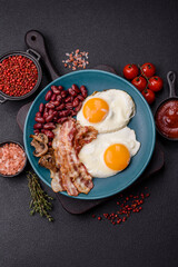 English breakfast with fried eggs, bacon, beans, tomatoes, spices and herbs