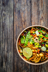 Takeaway food - Asian style stir fried vegetables and noodles on wooden table	