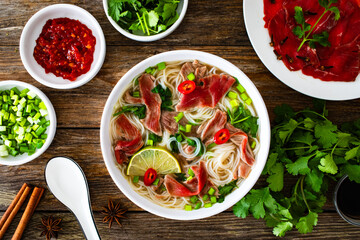 Pho soup - Vietnamese soup with beef on wooden table