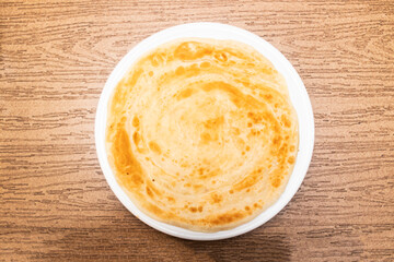 lachha paratha served in plate isolated on wooden table side view of bangladeshi food