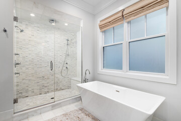 A bathroom detail with a freestanding bathtub with a chrome faucet and a large shower with small rectangle marble tiles, a bench seat, and chrome faucets.