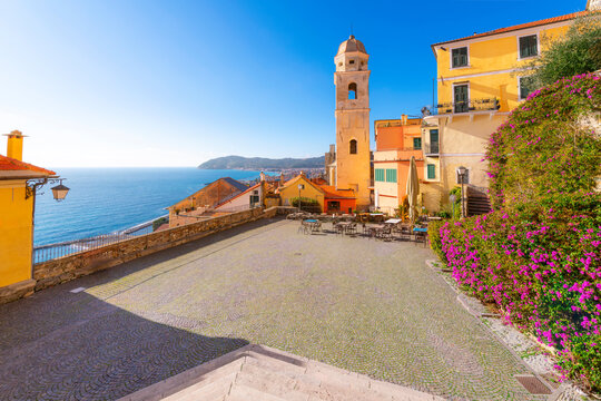 The colorful Piazza San Giovanni with the Palazzo Vento tower and sidewalk cafe overlooking the Ligurian Sea at the medieval seaside hill town of Cervo, Italy.