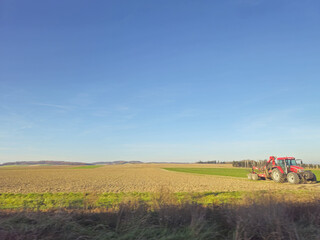 Fototapeta premium Tractor on a green field. Agricultural machinery on a sunny day.