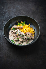 Traditional Swiss Zürcher geschnetzeltes from veal with mushrooms spaetzle in cream sauce served as close-up in a design bowl