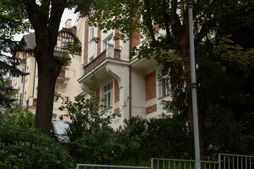 A spacious and large house is beautifully surrounded by green trees and lush bushes, creating a tranquil and serene environment