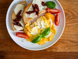 Continental breakfast - scrambled eggs, bruschetta and fresh vegetables on wooden table