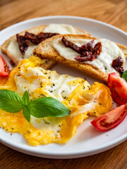 Continental breakfast - scrambled eggs, bruschetta and fresh vegetables on wooden table