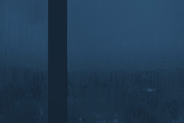Dark night window with fogged glass with water drops