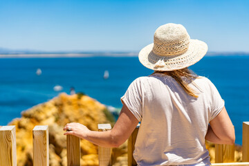 Summer vacation in Lagos Portugal. Mature woman tourist standing on viewpoint on cliffs during...
