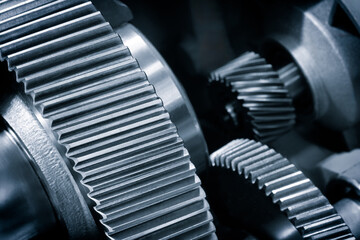 A close up of a gear with many teeth. The gear is part of a machine and is made of metal in blue