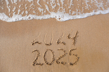 2024, 2025 years written on sandy beach sea. Wave washes away 2024. Happy New Year!