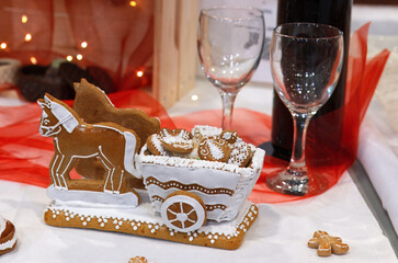 Horses pulling a wagon with a load of small cookies, made from edible gingerbread and decorated with sugar glaze. A cute decoration on Christmas dining table.