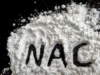 White powder on a black background. Letters NAC. Vitamines and bio hacking concept. Copy space
