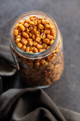 Roasted salted corn snack in jar on black table.