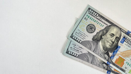 Close-up of two 100 US dollar bills angled on a white background, providing ample copy space. Ideal for use in financial advertisements, banking promotions, or educational content about currency and f