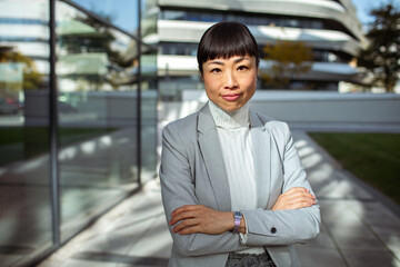 Confident businesswoman in formal attire standing outside modern office building